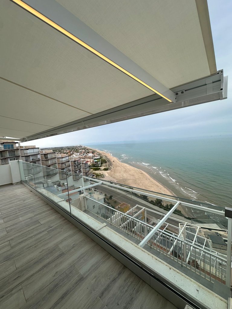 Toldo con cofre y lona blanca desplegado en un ático con vistas al mar en Cullera