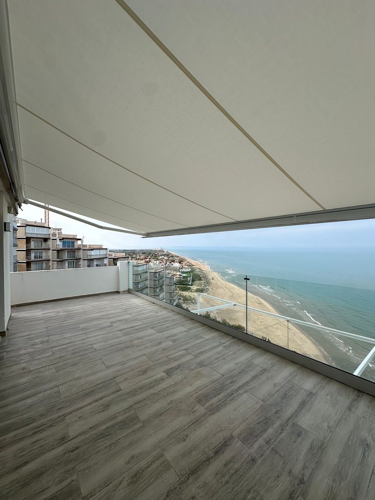 Toldo motorizado con cofre blanco en una terraza sobre el mar en Cullera