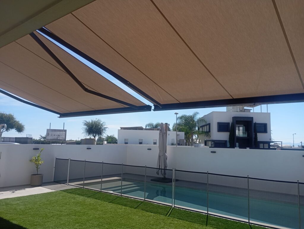 Dos toldos cofre Storbox 400 SQ abiertos sobre el jardín y la piscina de una vivienda en Albal